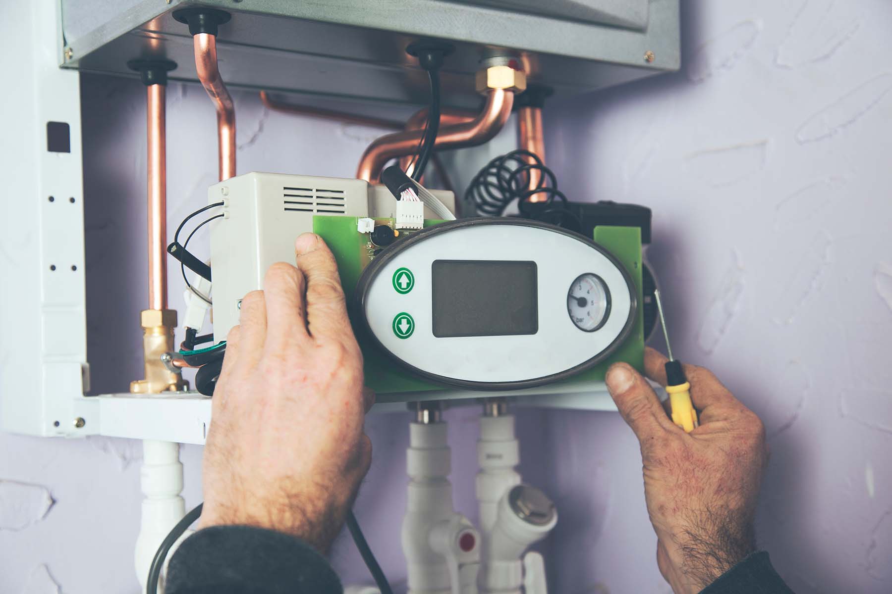 Engineer adjusting thermostat for efficient automated heating system